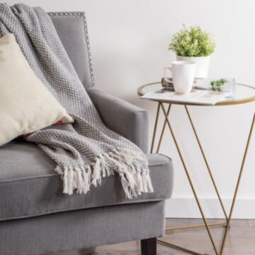 gray cotton basket weave throw blanket with tassels draped over armchair