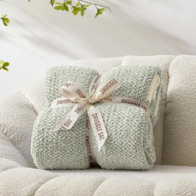 Cozy Porch Ideas for Relaxing Outdoor Spaces | Willow Haven Co sage green heather knit throw blanket folded with ribbon