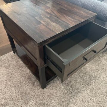 Rustic wood end table with drawer open showing storage space in a cozy living room